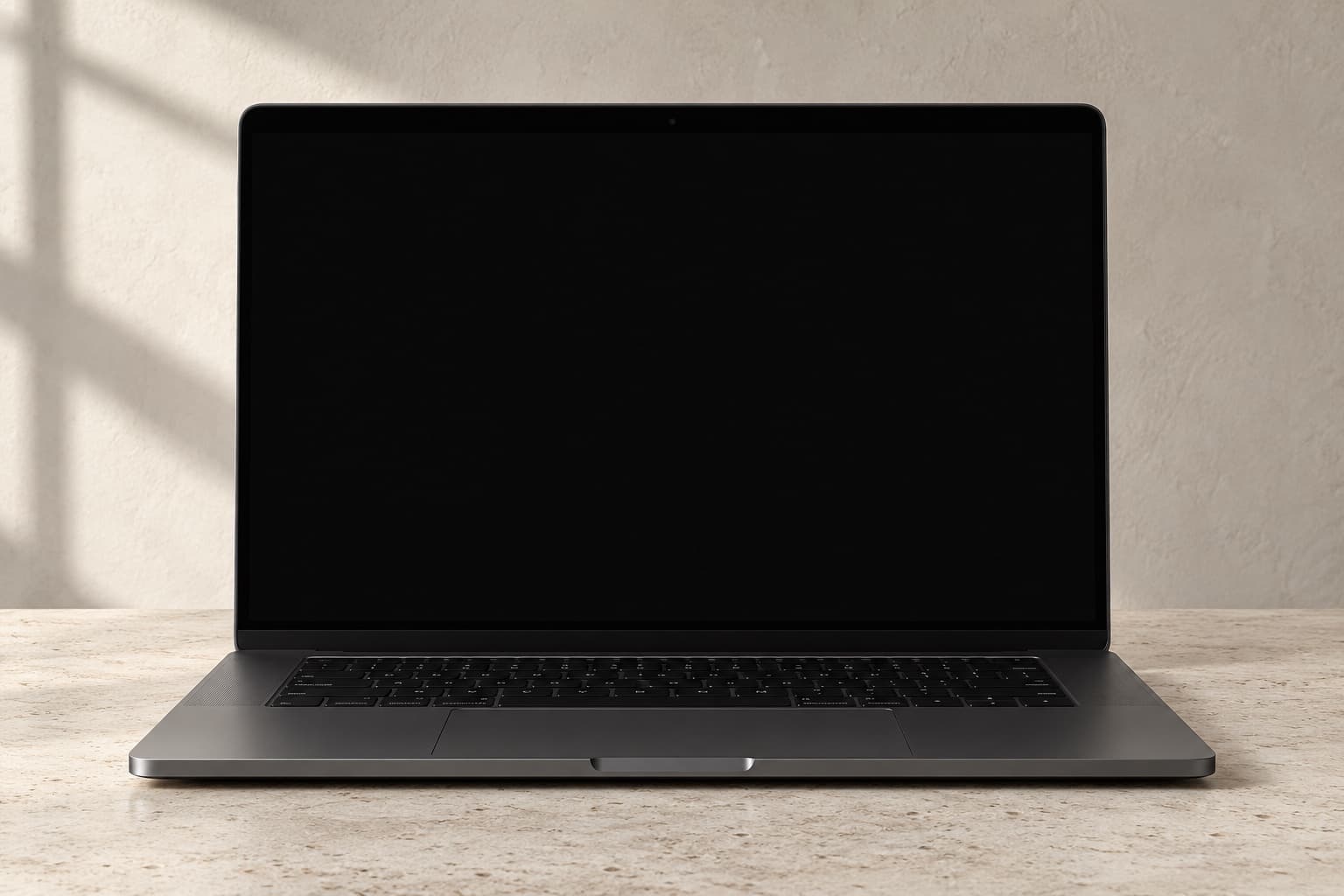 Geöffnetes MacBook auf hellem Naturstein vor einer Wand im Tageslicht